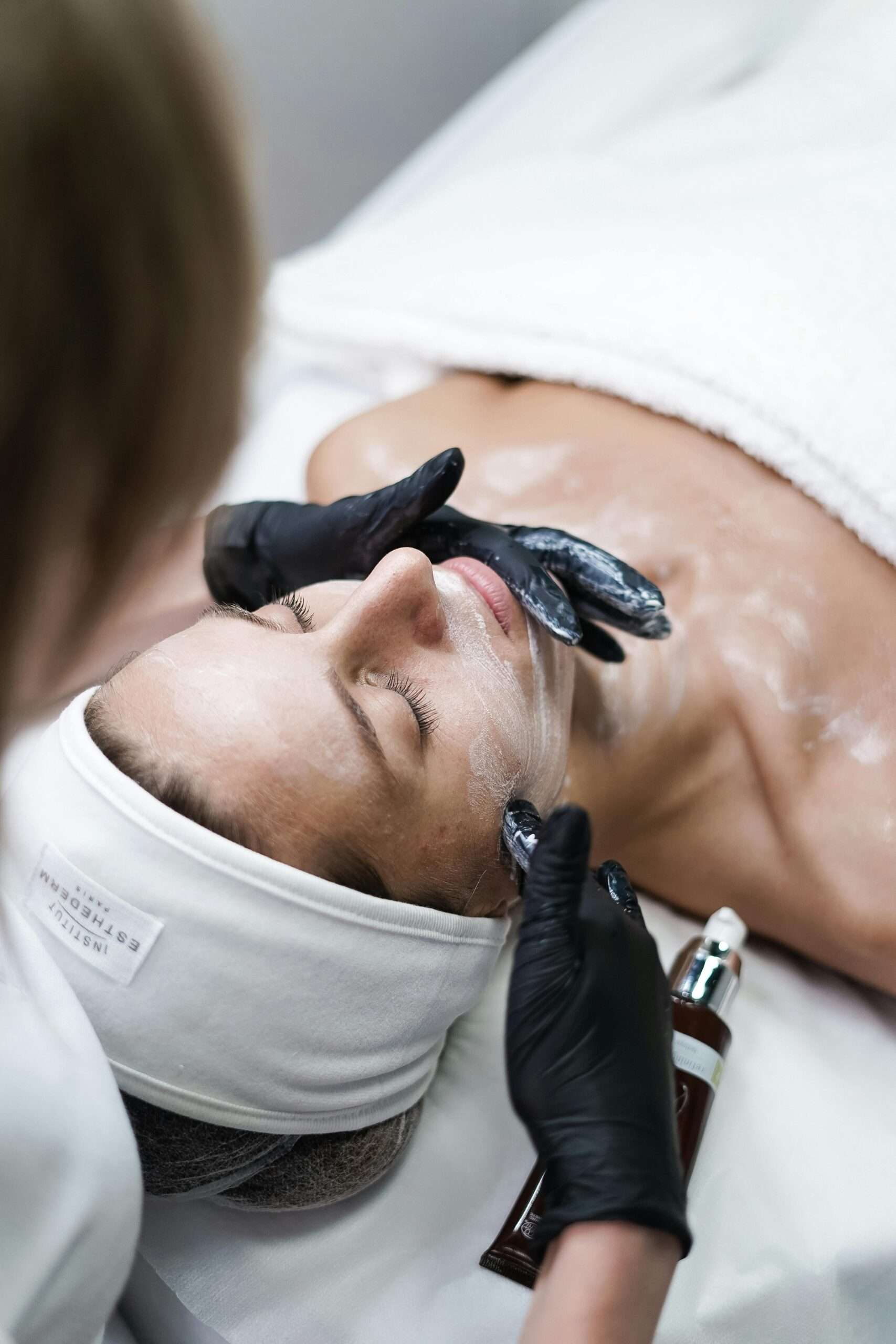 Beautician Removing Clay Cosmetic Mask from Woman Face